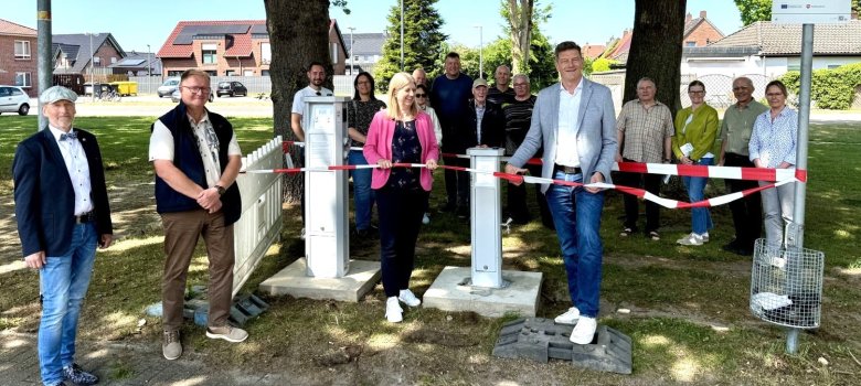 Vorsitzende des Ausschusses für Wirtschaft und Kultur, Maike Tramann und Bürgermeister Christoph Reents (Mitte) durchschneiden im Beisein von Projekt-Beteiligten und Gästen das symbolische Band.