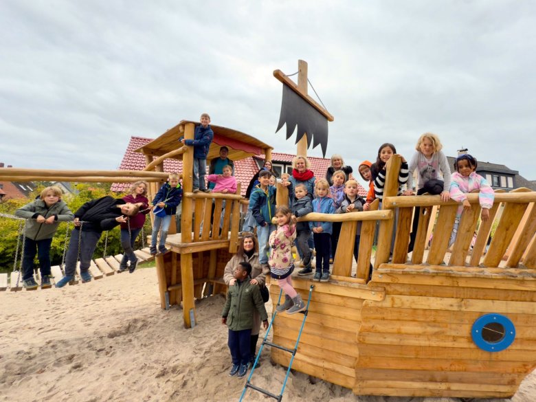 Die Kinder des Hortes Wardenburg mit pädagogischen Fachkräften sowie die in der Gemeindeverwaltung für Spielplätze zuständige Mitarbeiterin Julia Tscheslog (vor dem Mast). 