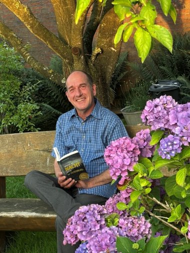 Foto von Kasten Rauchfuß mit Buch auf der Bank sitzend